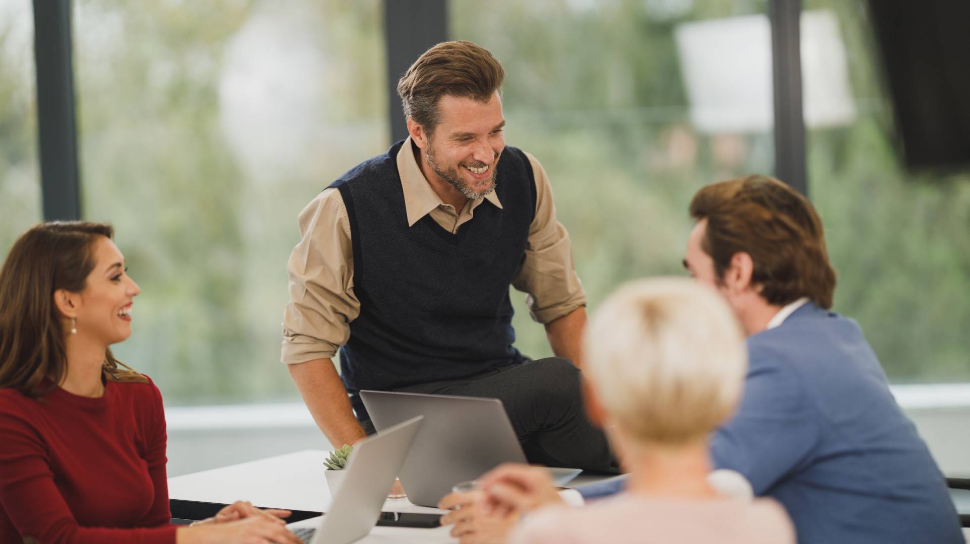 Four business people sitting and standing around a table in an office